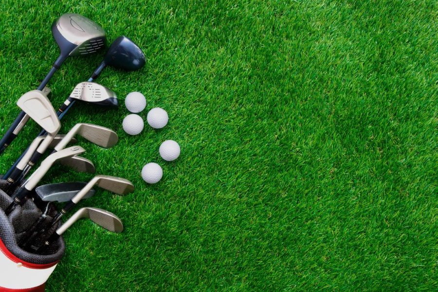 Golf ball and golf club in bag on green grass